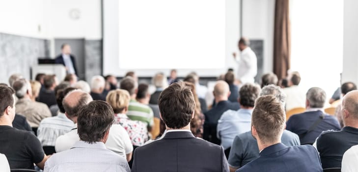 I have a question. Group of business people sitting at the chairs in conference hall. Businessman standing up asking a question. Conference and Presentation. Business and Entrepreneurship.