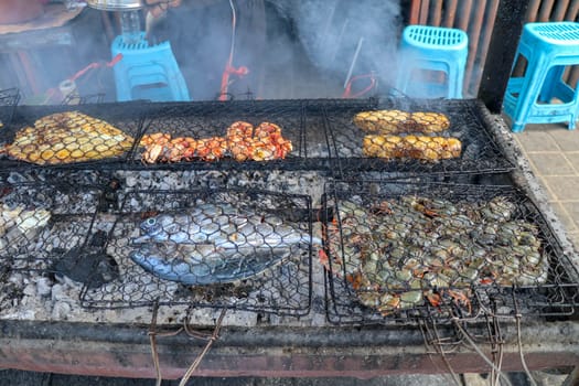 Fish barbecue. Cooking BBQ seafood on fire. Grill with burning coals. barbecue in excellent warung at the fish market on tropical Bali island in Jimbaran. Fresh, healthy and delicious seafood.