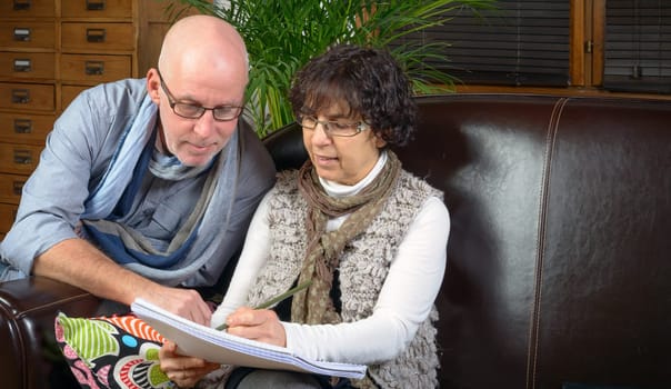 senior couple looking a book on a sofa