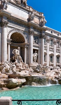 the facade of the Trevi Fountain in Rome, one of the main tourist attractions in Italy. Baroque architecture and sculpture. Historic building facade. Water flowing from the fountain. Sunny summer day