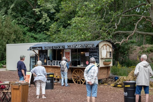 BEELITZ, GERMANY - JUN 30, 2020: Social distancing. People in the park want to buy pizza, grilled sausages or other food for lunch. Very disciplined, the rules of distance are observed during Coronavirus COVID-19 to avoid spreading.