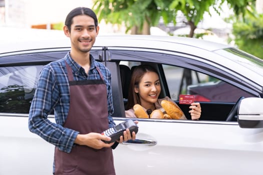 Portrait of asian woman make mobile payment contactless technology for online grocery ordering and drive thru service. Drive through and food online is new normal popular after coronavirus pandemic.