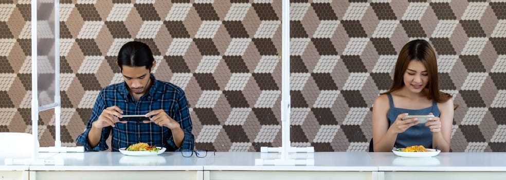Panoramic two asian influencer food blogger or vlog take food photo at new normal social distance restaurant with table shield partition. Restaurant new normal lifestyle and food influencer concept.