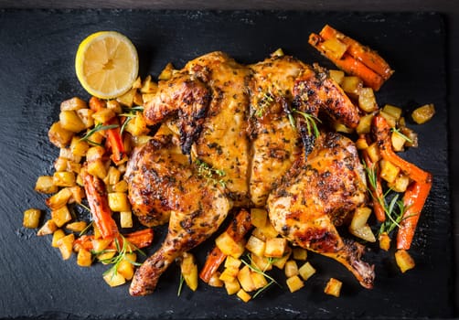 Butterflied grilled whole chicken with roasted vegetables and potatoes. Roadkill chicken style with herbs and lemon.