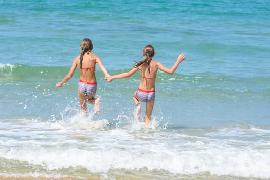 Girlfriends ran into the sea, view from the back