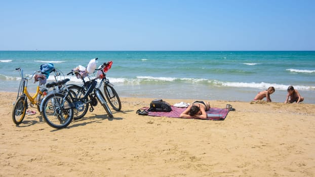 On the sandy seashore, a family arriving on bicycles rests