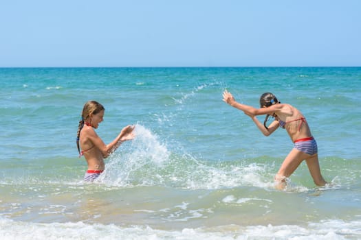 Girls splash on each other on the sea coast