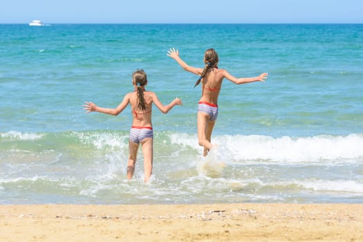 Cheerful children run to swim in the sea