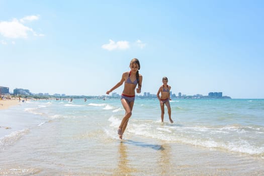 Two girlfriends run along the coastal strip of the sea coast
