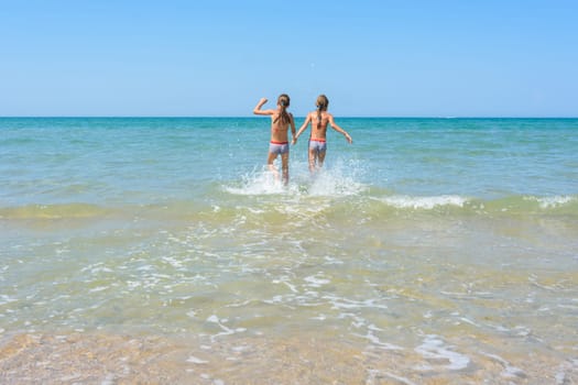 Girls run in the water swimming in shallow water