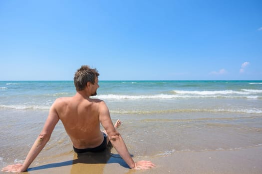 A man sits on the seashore and looks into the distance