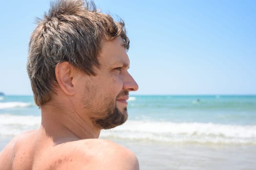 Portrait of an overgrown man of forty years against the background of the sea