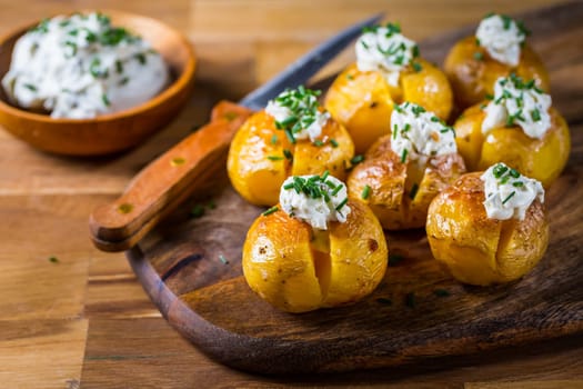 Small oven baked potatoes with sour cream with butter and chives