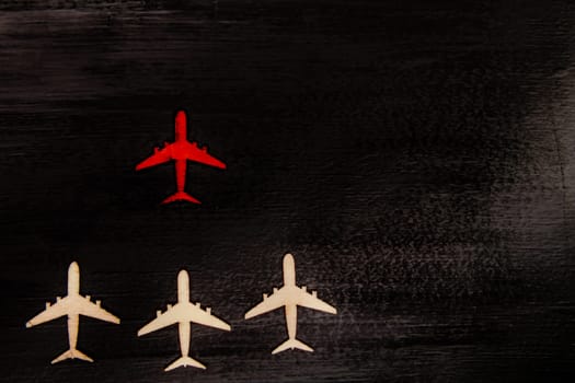 Wooden cutout planes with red plane in front leading them, leadership concept