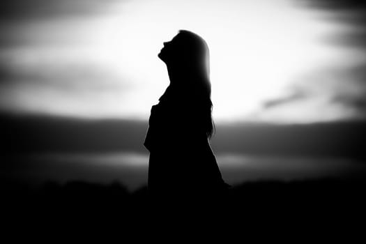 Silhouette in front of sunset or sunrise in summer nature. Symbol for healing burnout therapy, wellness relaxation or resurrection.