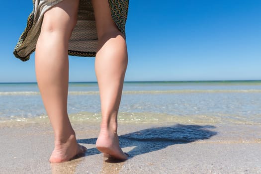 Close-up of a woman's legs on the seashore. View at ground level.