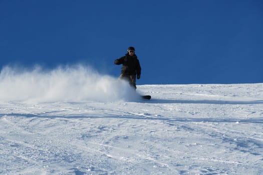 Snowboarder carving a turn on the piste