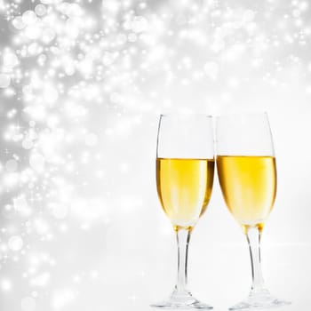 Glasses with champagne against fireworks and silvery background