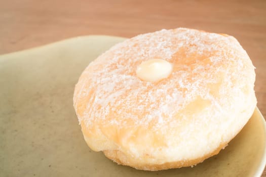 Cream donut on vintage background, stock photo