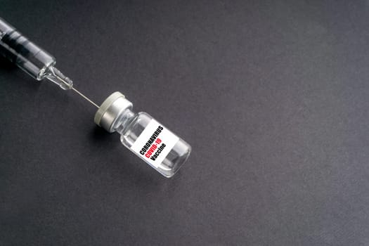 CORONAVIRUS COVID-19 VACCINE text with syringe and vials on black background. Covid-19 and Coronavirus concept