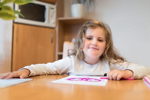 Smiling happy cute girl with long curly golden hair artist painting picture on paper. School homework concept