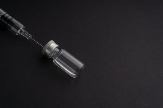 Closeup syringe and vials on black background. Healthcare dan Copy Space concept