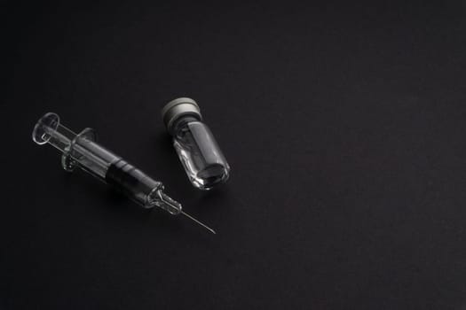 Closeup syringe and vials on black background. Healthcare dan Copy Space concept