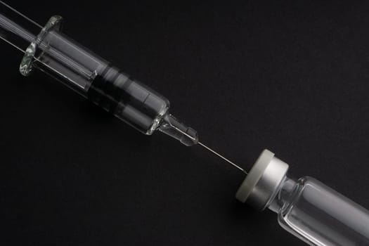 Closeup syringe and vials on black background. Healthcare dan Copy Space concept