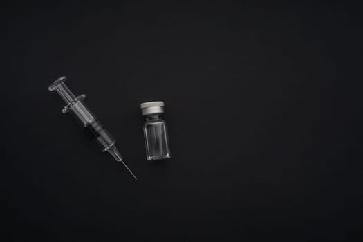 Closeup syringe and vials on black background. Healthcare dan Copy Space concept