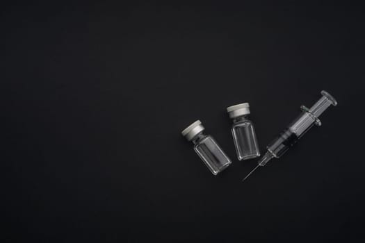 Closeup syringe and vials on black background. Healthcare dan Copy Space concept