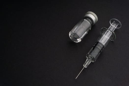 Closeup syringe and vials on black background. Healthcare dan Copy Space concept