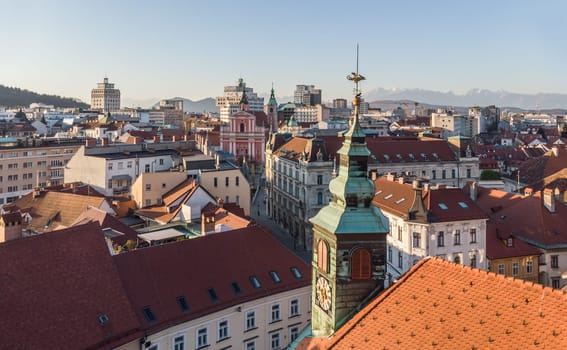 Scenic panoramic aerial drone view of rooftops of medieval city center, town hall and cathedral church in Ljubljana, capital of Slovenia, at sunset.