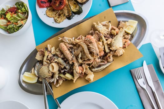 Delicious traditional fried sea food plate for two on summer vacation in traditional croatian costal restorant by the sea.