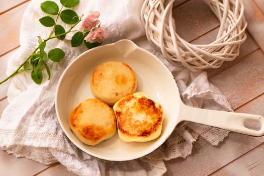Cast-iron frying pan with curd pancakes or syrniki, shabby table, flat lay