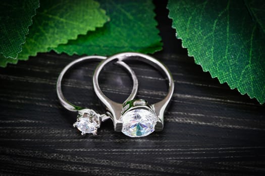 Close up Diamond gem wedding rings with green leaves on black background, Jewelry wedding diamond rings on black background
