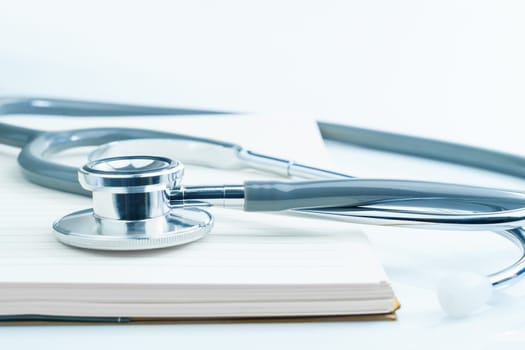 Close up Medical stethoscope for doctor checkup on health medical laboratory table with notepad as medical concept