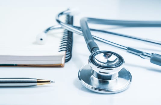 Close up Medical stethoscope for doctor checkup on health medical laboratory table with notepad as medical concept