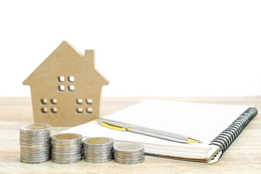 House model and notepad with coins on table for finance and banking concept