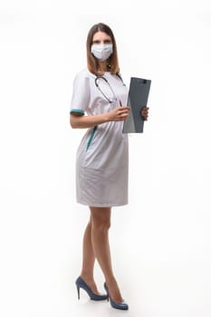 girl doctor in medical clothes and mask with tablet in hand on white background builds in full growth