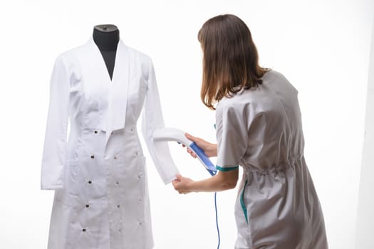 Girl in medical clothes handles steam clothes on manicure