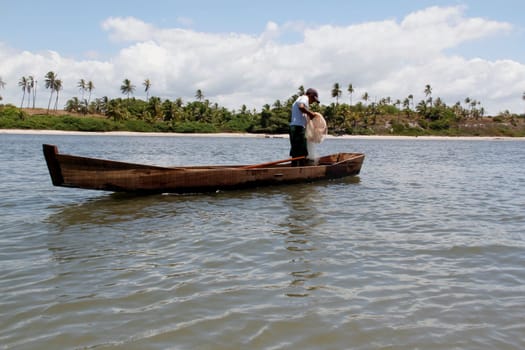 conde, bahia / brazil - march 28, 2013: fisherman is seen in a small boat near the mouth of the Itapicuru river in the district of Siribinha in the city of Conde, north coast of Bahia.