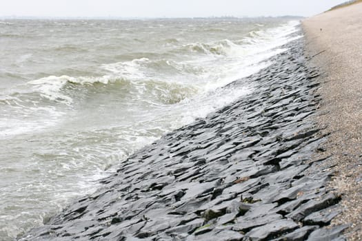 Detail view of a dam fortified with stones on the North Sea .