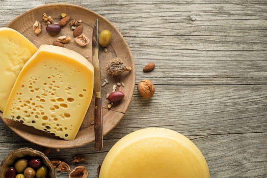 Assortment of cheese, nuts and fruits on a wooden table. Top view. Free space for text.