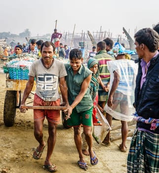 Chittagong, Bangladesh, December 23, 2017: Fishermen are pulling cart with fresh catch of shrimp at a market in Chittagong, Bangladesh