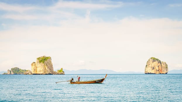 Krabi, Thailand, November 9, 2017: Thai long tail fishing boat in the Andaman Sea with islands and Krabi coastline on the horizon