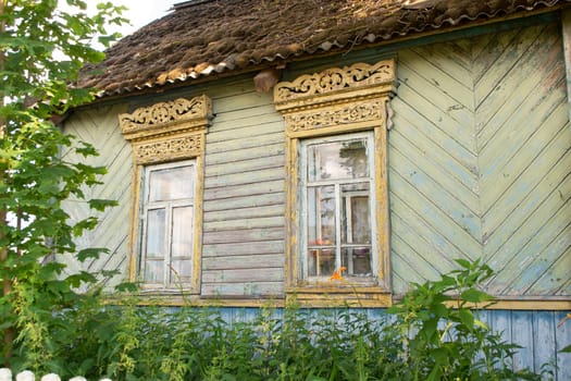 Old wooden shabby house in village in Belarus. Windows and bushes