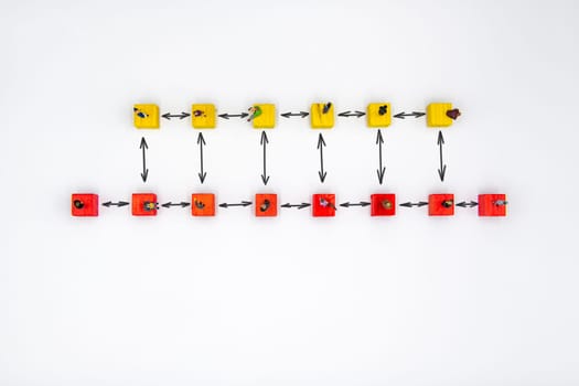 Miniature figurines standing socially distanced on wooden cubes with drawn arrows isolated over white background