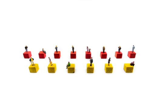 Miniature figurines standing socially distanced on wooden cubes isolated over white background