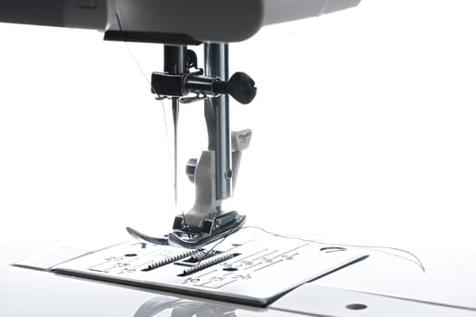 8 - Medium horizontal image of sewing machine working area. Plate foot needle thread and housing above is all visible.