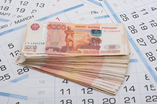 On the sheets of the calendar are stacks of five thousandth bills